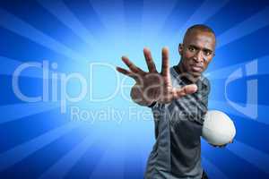 Composite image of close-up portrait of sportsman gesturing while standing with rugby ball