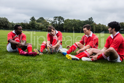 Rugby players sitting on grass before match