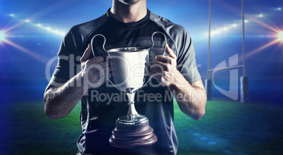 Composite image of victorious rugby player holding trophy