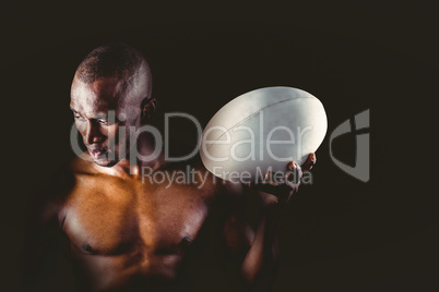 Concentrated shirtless sportsman holding rugby ball