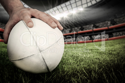 Composite image of a rugby player posing a rugby ball