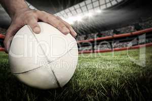 Composite image of a rugby player posing a rugby ball