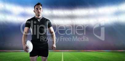 Composite image of tough rugby player holding ball