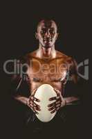 Portrait of shirtless athlete holding rugby ball