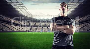 Composite image of confident rugby player with arms crossed