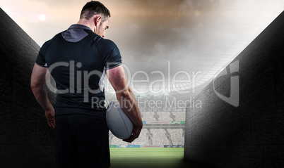 Composite image of tough rugby player holding ball