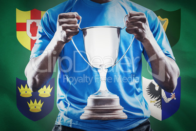 Composite image of mid section of sportsman holding trophy