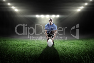 Composite image of portrait of rugby player holding ball while k