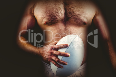 Shirtless rugby player holding ball