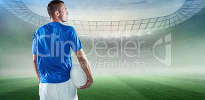 Composite image of rugby player looking away while holding ball