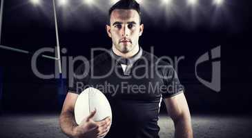 Composite image of tough rugby player holding ball