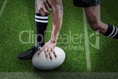 Composite image of low section of sportsman holding rugby ball