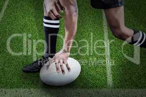 Composite image of low section of sportsman holding rugby ball