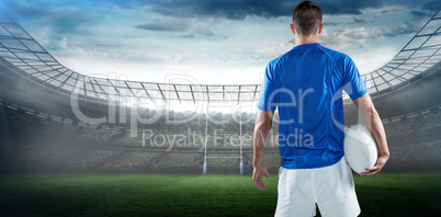 Composite image of rear view of rugby player holding ball aside
