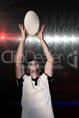 Composite image of rugby player catching the ball