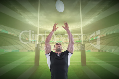 Composite image of rugby player catching the ball