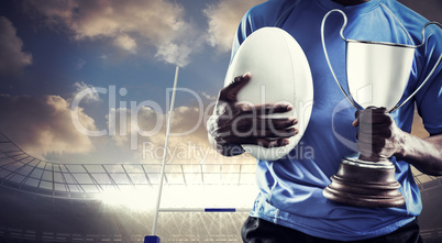 Composite image of mid section of sportsman holding trophy and r