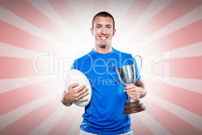 Composite image of portrait of smiling rugby player holding trop