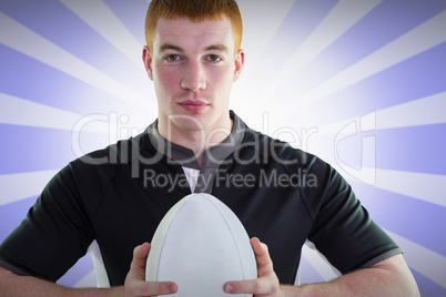 Composite image of smiling rugby player holding a rugby ball