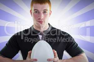 Composite image of smiling rugby player holding a rugby ball