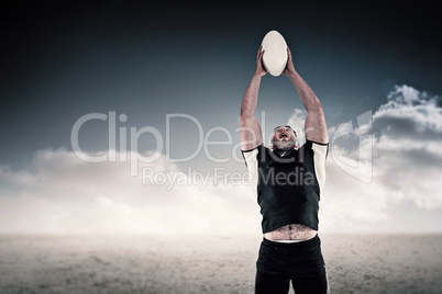 Composite image of rugby player catching the ball