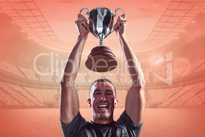 Composite image of portrait of successful rugby player holding t