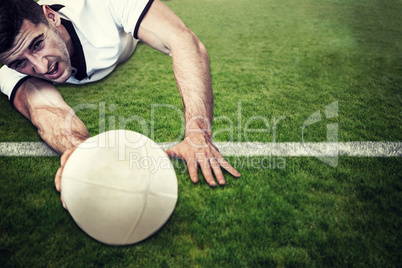 Composite image of man holding rugby ball while lying down