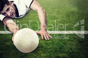 Composite image of man holding rugby ball while lying down