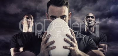 Composite image of tough rugby player holding ball