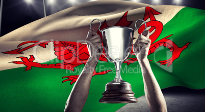 Composite image of successful rugby player holding trophy