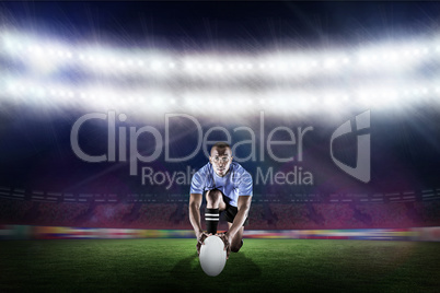 Composite image of portrait of rugby player kneeling and holding