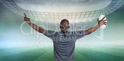 Composite image of rear view of sportsman with arms raised holding rugby ball