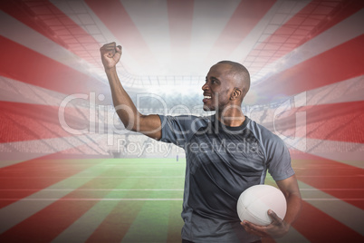 Composite image of sportsman with clenched fist holding rugby ba