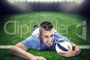 Composite image of confident rugby player lying in front with ba