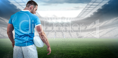 Composite image of rugby player standing with ball