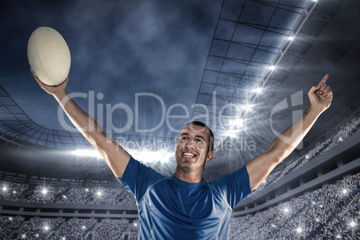 Composite image of happy rugby player in blue jersey holding bal