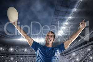 Composite image of happy rugby player in blue jersey holding bal