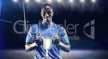 Composite image of portrait of happy athlete holding trophy