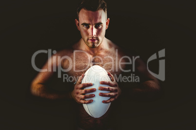 Shirtless rugby player holding ball