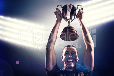 Composite image of portrait of successful rugby player holding t