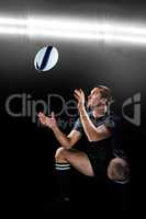 Composite image of full length of rugby player catching the ball