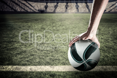 Composite image of rugby player with arm raised holding ball