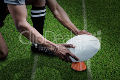 Composite image of cropped image of sportsman keeping rugby ball on kicking tee