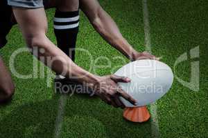 Composite image of cropped image of sportsman keeping rugby ball on kicking tee