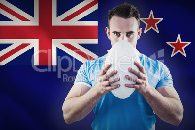 Composite image of rugby player looking at camera with ball