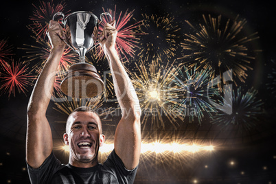 Composite image of portrait of successful rugby player holding t