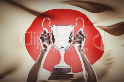 Composite image of cropped hand of athlete holding trophy