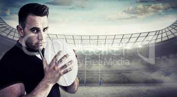 Composite image of tough rugby player holding ball