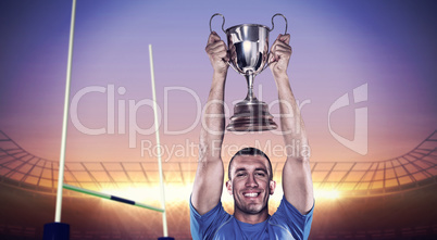 Composite image of portrait of smiling rugby player holding trop