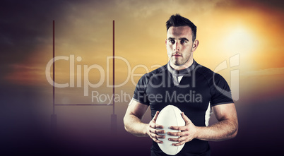 Composite image of tough rugby player holding ball